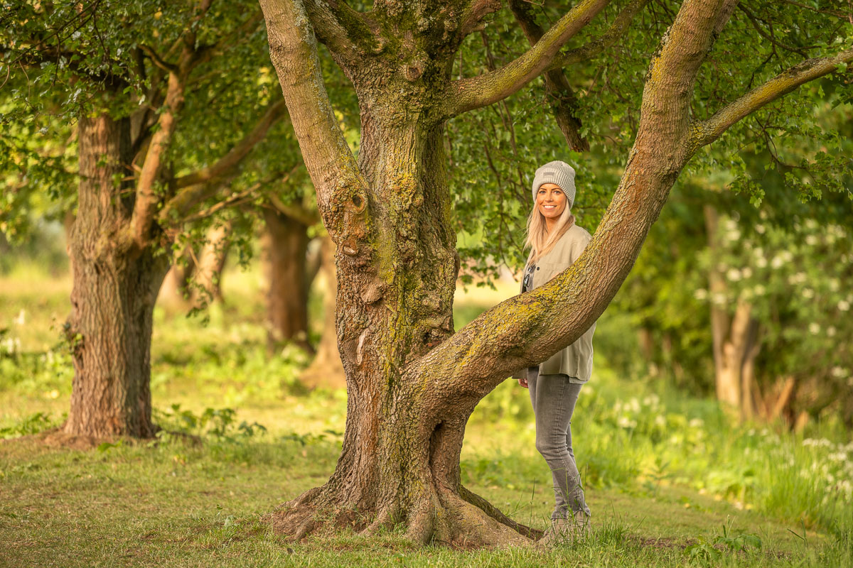 Frau steht hinter einem Baum im Grünen am Kemnader See im Ruhrgebiet