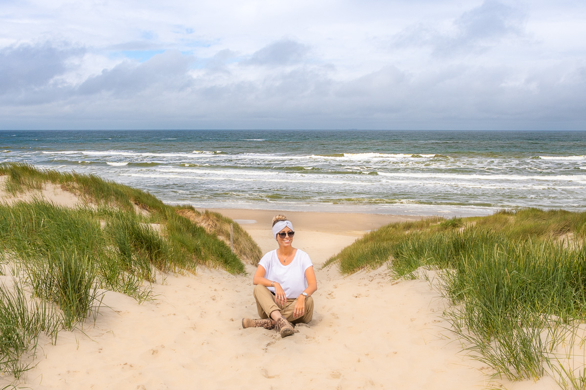 Frau sitzt am Strand der Nordsee auf Texel