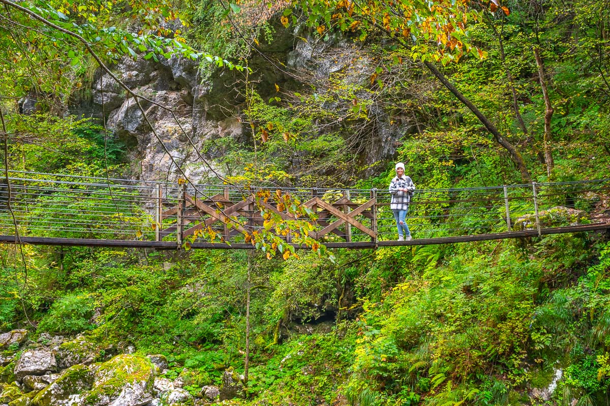 Frau steht auf hölzernen Hängebrücke im Soca Tal