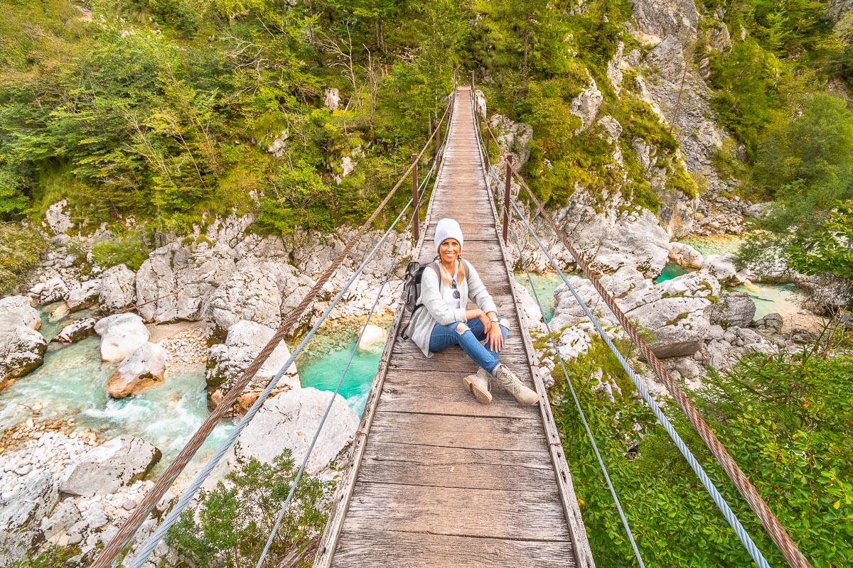 Frau sitzt auf Hängebrücke im Soca Tal