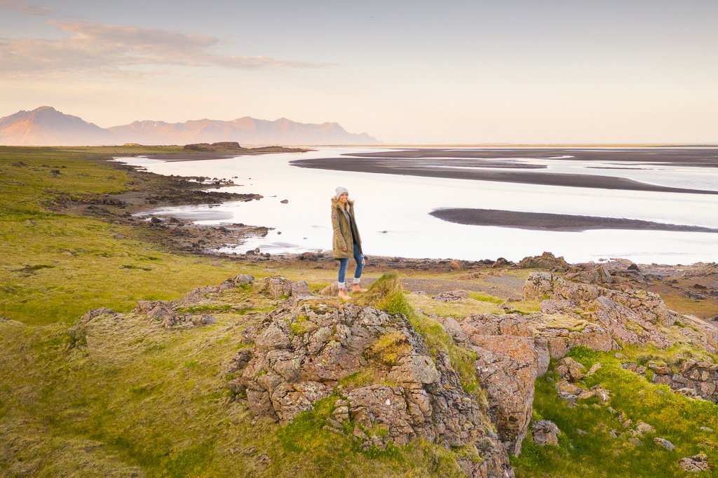 Frau steht in einer moosbewachsenen Landschaft auf Island